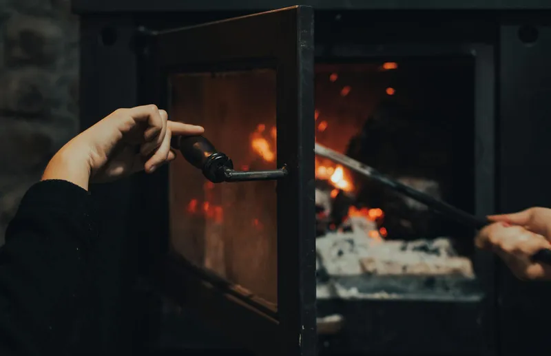 Hands maintaining and cleaning gas fireplace glass panel