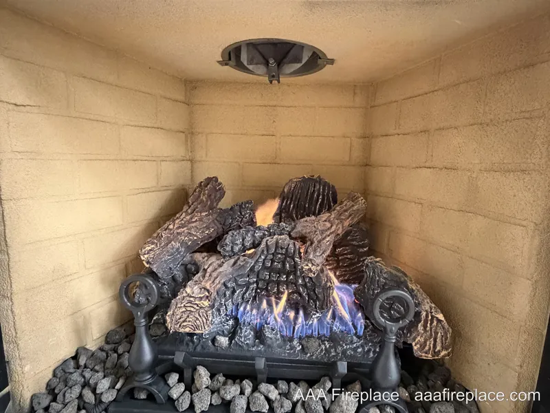 Completed vented gas log set with lava rock and andirons burning in the firebox